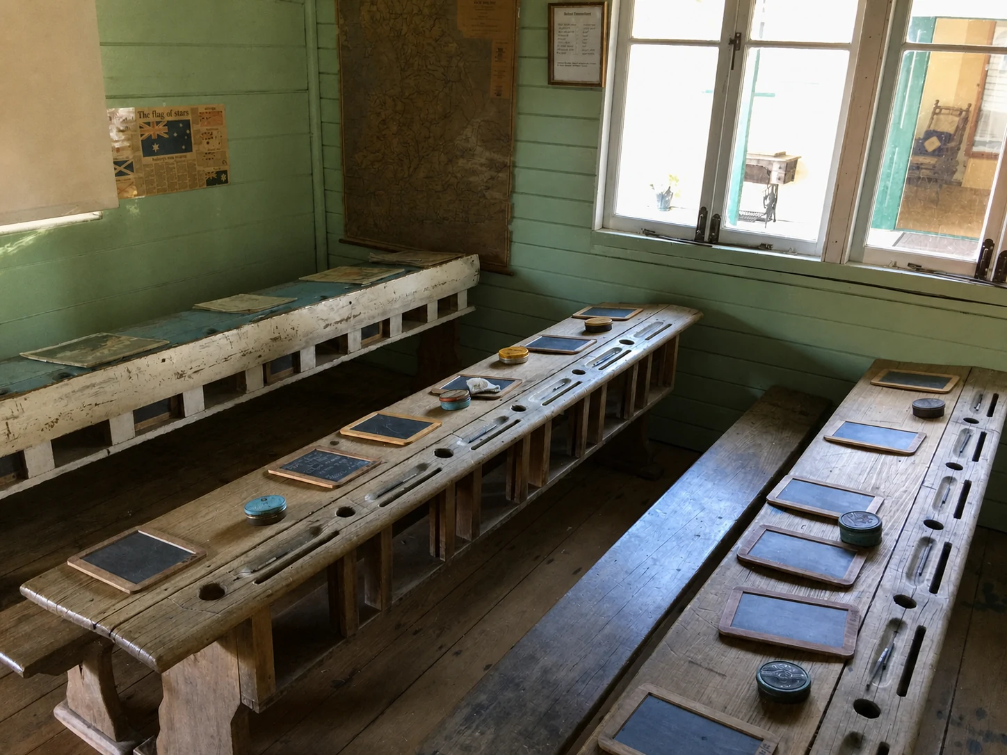 Wooden desks and slates in a historic schoolroom display at Hervey Bay Historical Village & Museum
