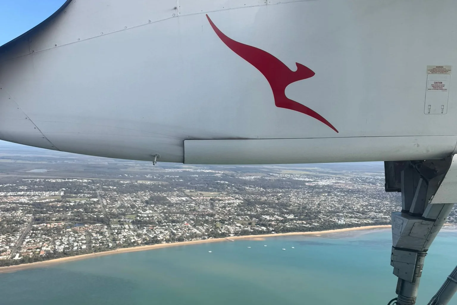 Qantas aircraft engine and landing gear with Hervey Bay in the background